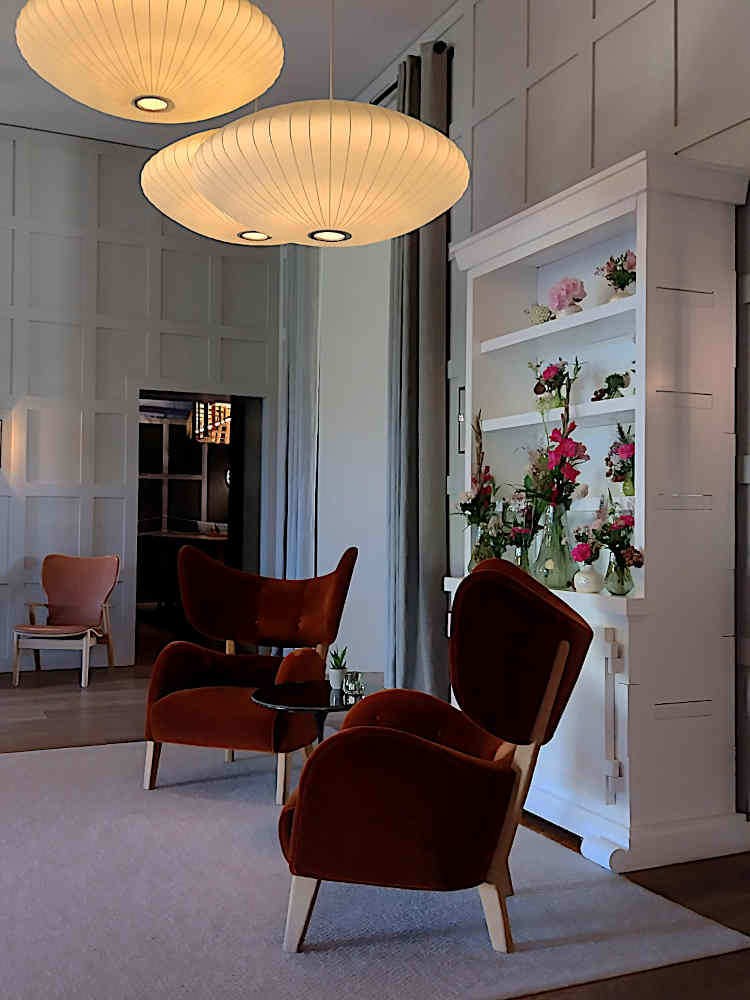 Das Vestibül im historischen Empfangsbau begrüßt die Gäste mit Designer-Lampen, extravaganten Sesseln und frischen Blumen.